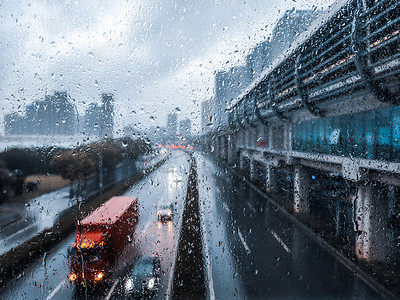 下雨天傍晚玻璃窗上雨滴窗外马路车流和车灯