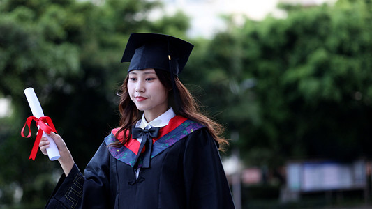 毕业黑板摄影照片_手拿毕业证书黑板穿学士服的大学毕业生