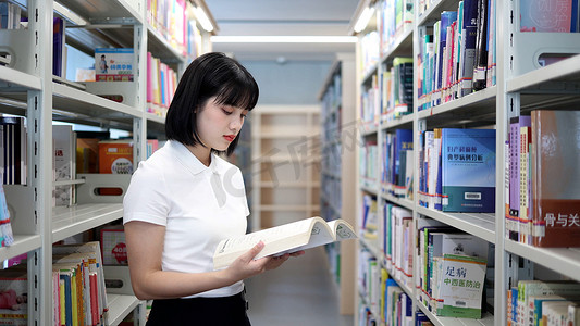 图书馆女生摄影照片_图书馆看书的女大学生学习阅读书写作业