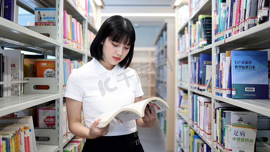 校园生活摄影照片_图书馆看书的女大学生学习阅读书写作业
