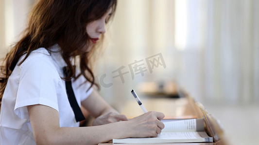 校园里的女大学生学习阅读读书写作业