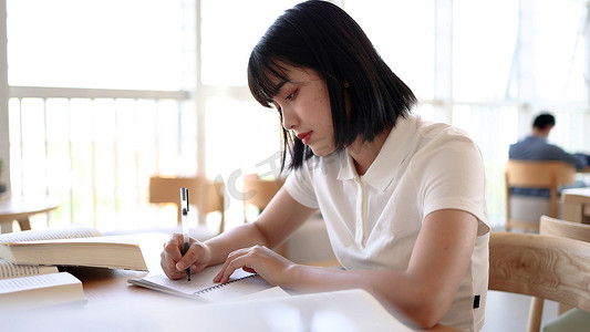 书写女孩摄影照片_图书馆看书的女大学生学习阅读书写作业