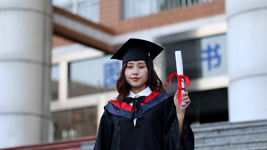 毕业照毕业照摄影照片_手拿毕业证书黑板穿学士服的大学毕业生
