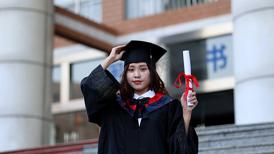 手拿毕业证书黑板穿学士服的大学毕业生