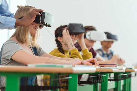 十几岁背景图片_非洲裔美国人教师的裁剪图像调整虚拟现实耳机到十几岁的女生与同学坐在后面