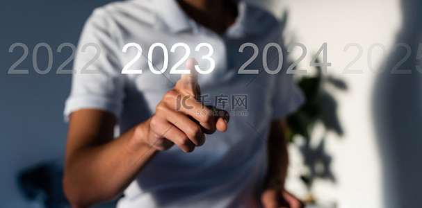 2023蓝色背景背景图片_手指在灰色背景的虚拟界面上按蓝色启动2023按钮，并为文本提供复制空间。新年的概念。商人在2023年开业。新春2023年开始