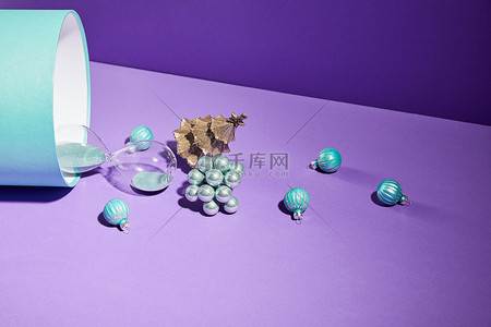 沙漏紫色背景图片_Christmas decoration and hourglass scattered from blue gift box on purple background