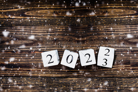 木制的白色日历块翻动着2022年至2023年的新年。降雪的桌面视图.