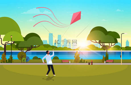 年轻人推出风筝户外现代公共公园家伙玩风玩具假日概念城市景观日落背景水平平