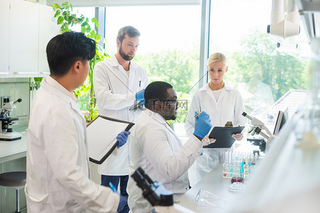 化学生物背景图片_科学家和在实验室工作的学生。教授实习生进行血液分析研究。实验工具:显微镜、试管、仪器.生物技术、化学、细菌学、病毒学