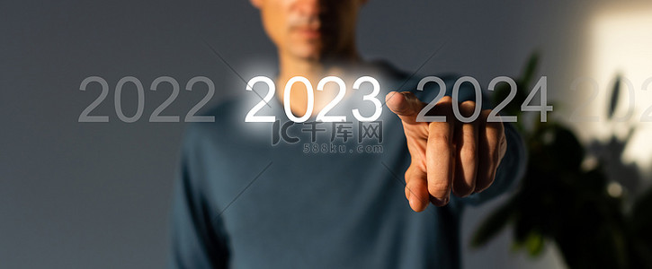 新年按钮背景图片_手指在灰色背景的虚拟界面上按蓝色启动2023按钮，并为文本提供复制空间。新年的概念。商人在2023年开业。新春2023年开始
