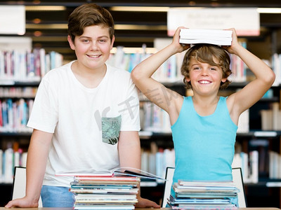 两个男孩在图书馆里带着书。图书馆里的两个男孩