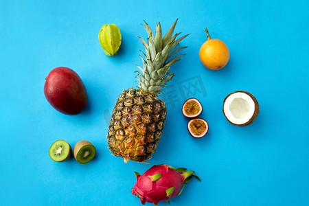 食物，夏天和健康饮食概念—菠萝与其他异国情调的水果在蓝色背景。菠萝与其他水果在蓝色背景