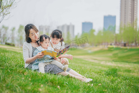 在看书摄影照片_妈妈坐在草地上陪两个孩子看书