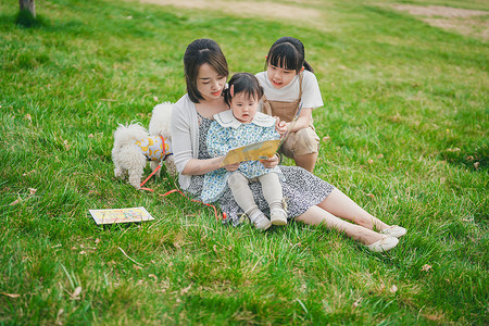 妈妈坐在草地上陪孩子看书