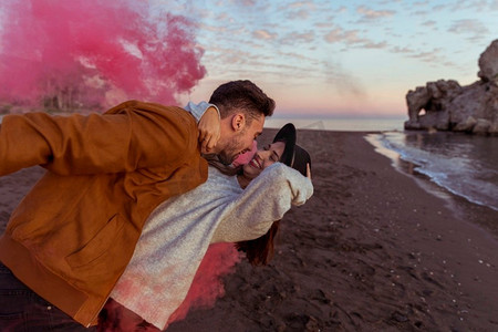 男人拥抱女人与粉红色烟雾弹海岸