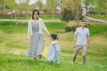 孩子爸爸妈妈摄影照片_小女孩和爸爸妈妈在公园草地上玩耍