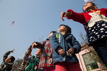 放飞机男孩摄影照片_乡村小学生在学校放纸飞机