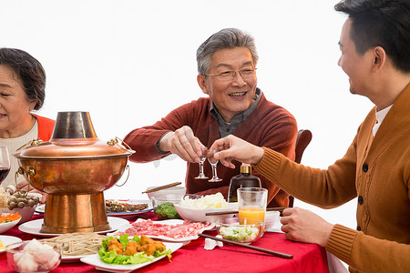 老年人喝酒摄影照片_父子俩吃年夜饭喝酒