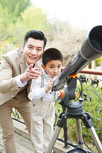 阳台人摄影照片_父亲和儿子在阳台使用天文望远镜