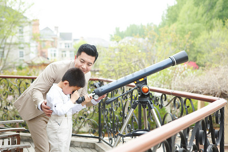 父亲和儿子在阳台使用天文望远镜