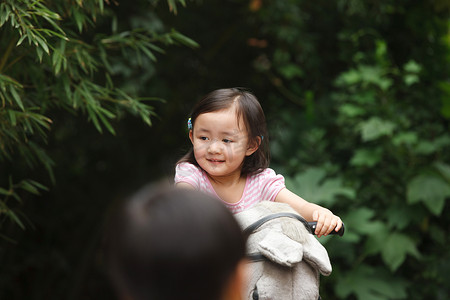 动物幼儿园摄影照片_可爱的小女孩在骑摇摆木马