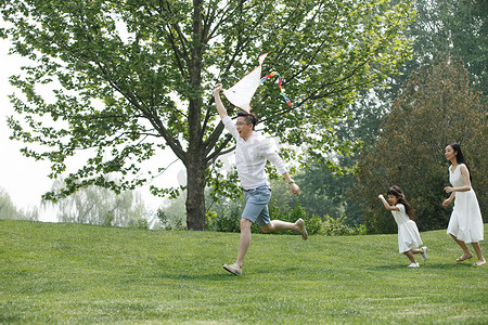 风筝摄影照片_一家三口在草地上放风筝