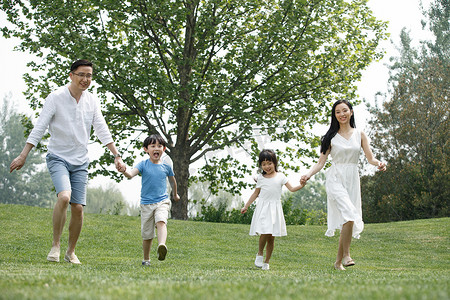 儿童跑的动作摄影照片_快乐家庭在草地上奔跑