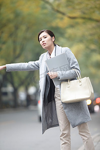 手势交通摄影照片_青年女人在路边等出租车