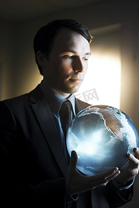 商务科技发光摄影照片_特写一个商务男人手捧发光放射的数码地球
