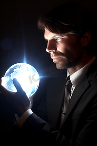 商务科技发光摄影照片_特写一个商务男人手捧发光放射的数码地球
