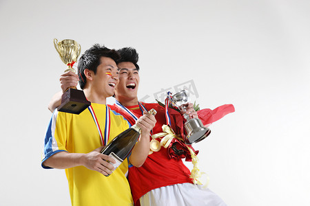 红色荣誉摄影照片_两个东方男运动员手拿奖杯