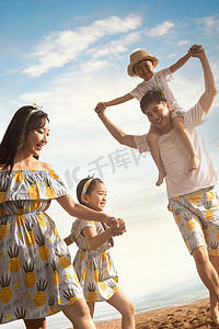儿童托举摄影照片_幸福的一家四口在沙滩上散步