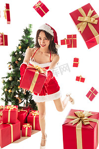 圣诞高跟鞋摄影照片_穿着圣诞服的年轻女人拿着圣诞礼物