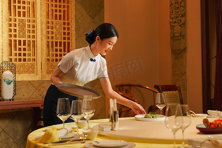 中式宴会摄影照片_热情的酒店服务员上菜