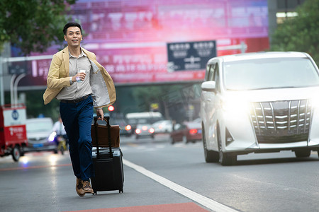 奔跑的人物商务摄影照片_马路上拉着行李追赶汽车的商务男子