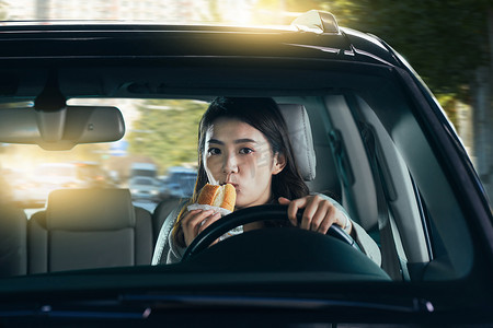 驾驶汽车的青年女人吃食物