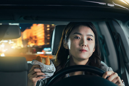 女司机图片摄影照片_驾驶汽车的青年女人吃食物