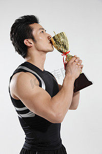 东方男青年运动员亲吻奖杯