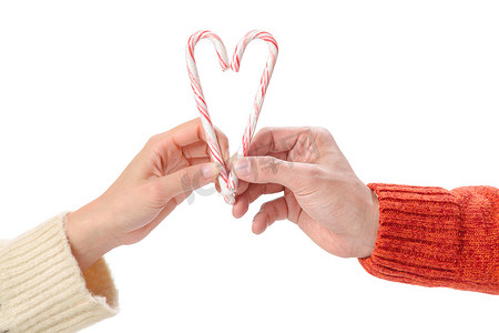 圣诞糖果拐杖摄影照片_青年情侣拿着拐杖糖组成心的形状