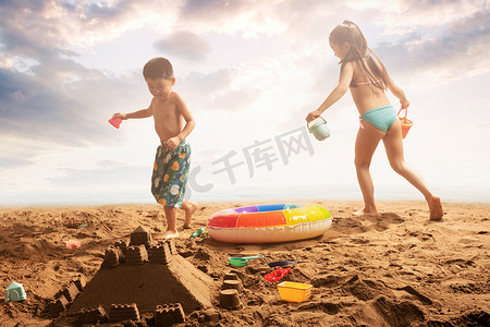 儿童游泳圈摄影照片_快乐的东方儿童在沙滩上玩耍