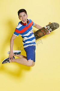 青春欢呼摄影照片_青年男人拿着滑板