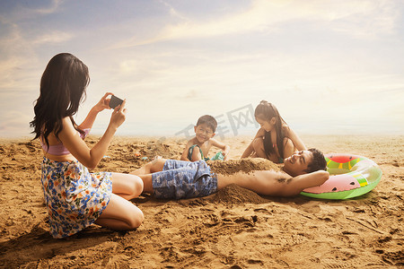 沙滩上青年女人为丈夫孩子拍照