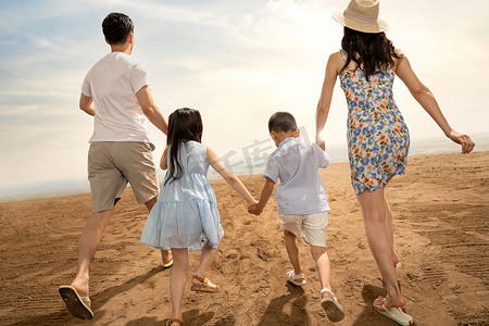 幸福一家四口在沙滩上奔跑的背影