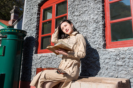 青年女人坐在火车站站台上看书