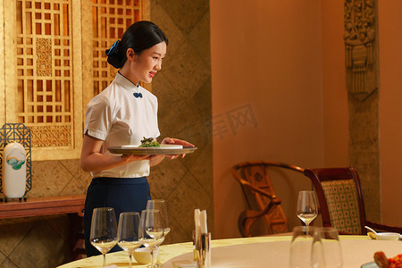 中式宴会摄影照片_热情的酒店服务员上菜