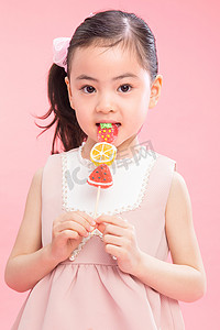 棒棒糖粉色背景摄影照片_可爱的小女孩