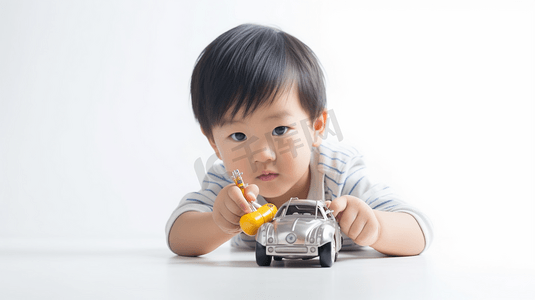 拿玩具汽车的男孩摄影照片_4岁左右的亚洲男孩拿着小螺丝螺丝刀在白色背景上修理汽车玩具
