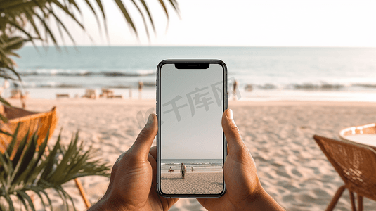 一个男人坐在沙滩上，拿着空白桌面的手机的模拟图像
