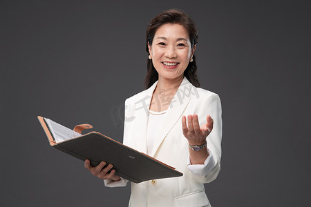 拿着户型图册做出邀请手势的优雅商务女士